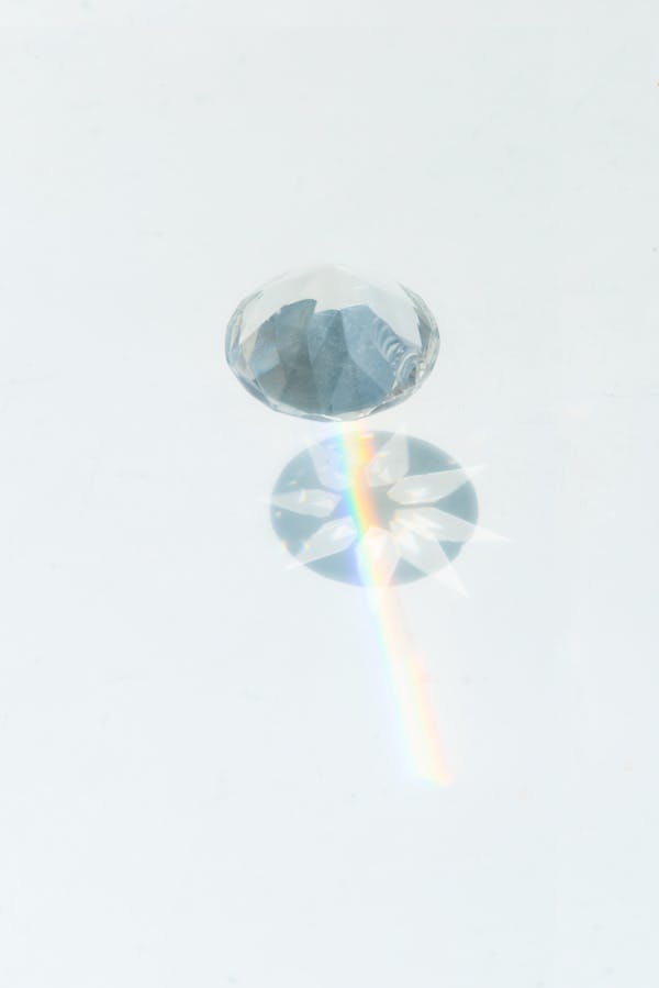 A sparkling diamond casting vibrant rainbow reflections on a smooth white background.