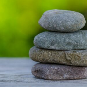 Four smooth stones stacked outdoors, symbolizing balance and tranquility.